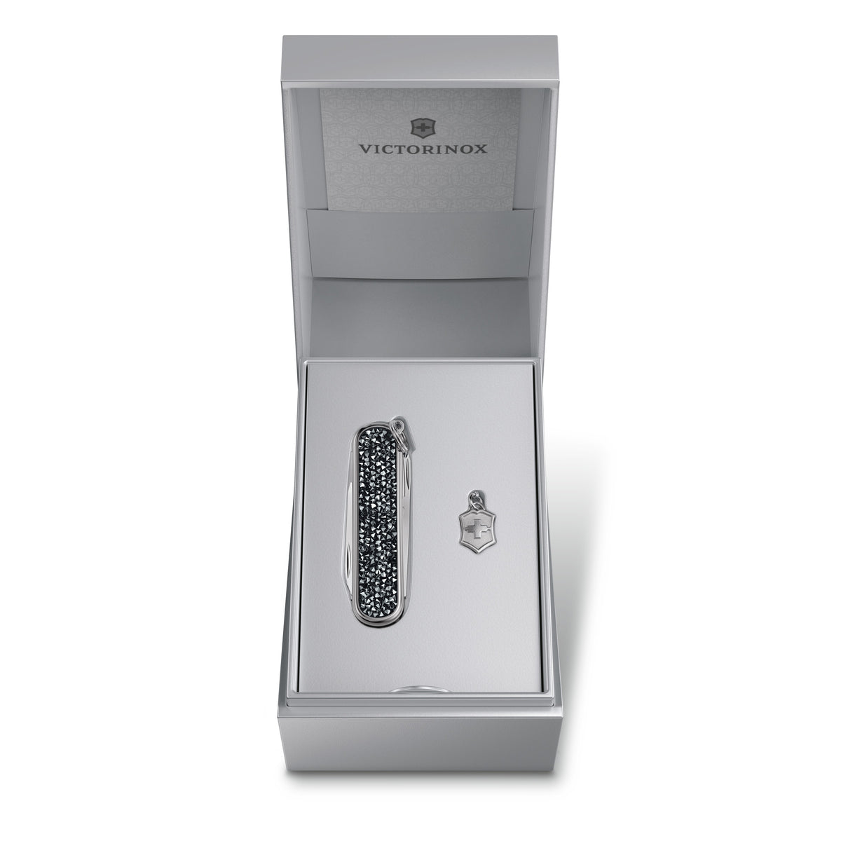Open silver gift box with compact multi-tool and keyring shield charm